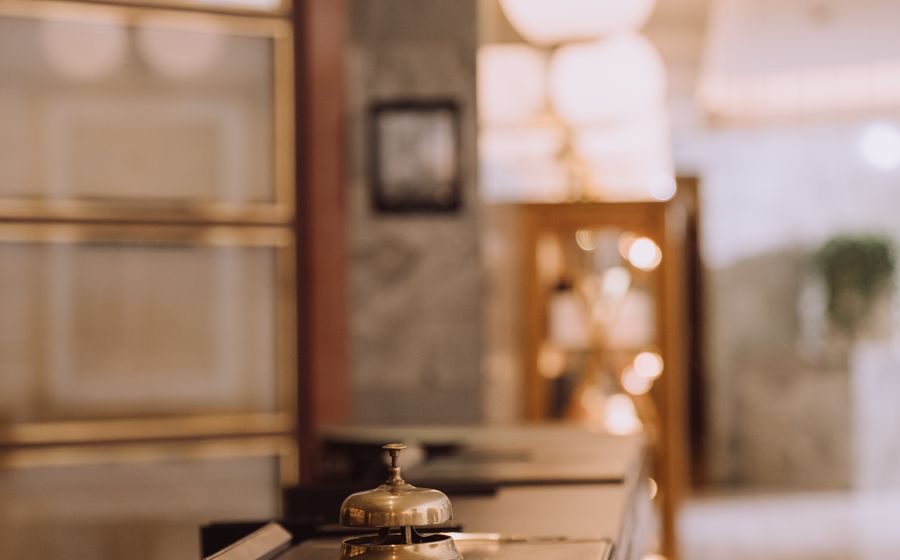 Mostrador de recepción de madera con un timbre de latón encima y el fondo desenfocado.