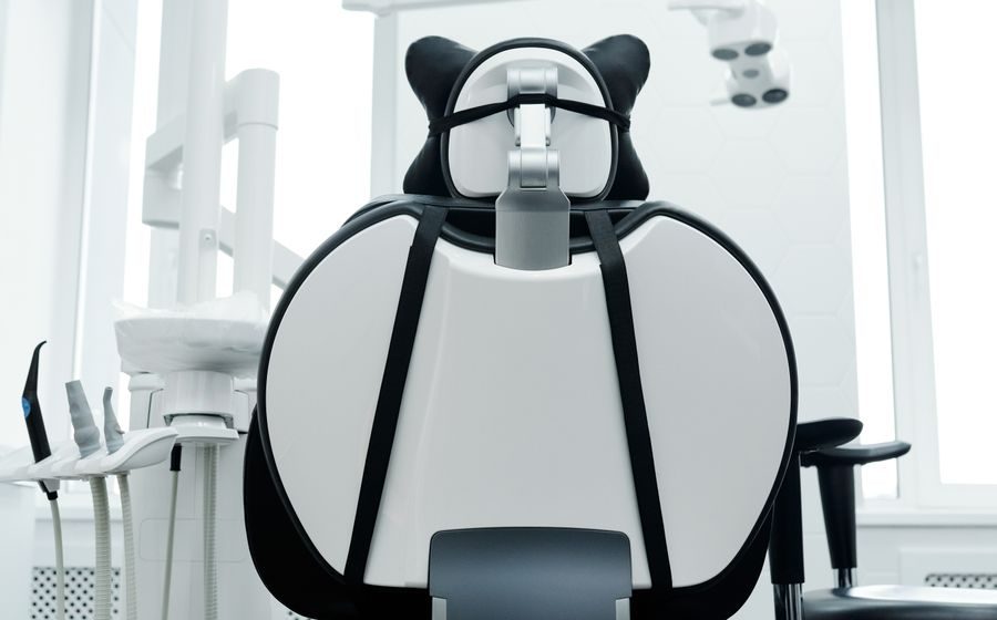 Sillón de una consulta dental visto desde atrás, con el instrumental recogido a un lado.