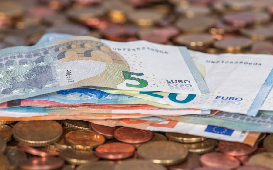 Billetes de euro doblados sobre un montón de monedas.