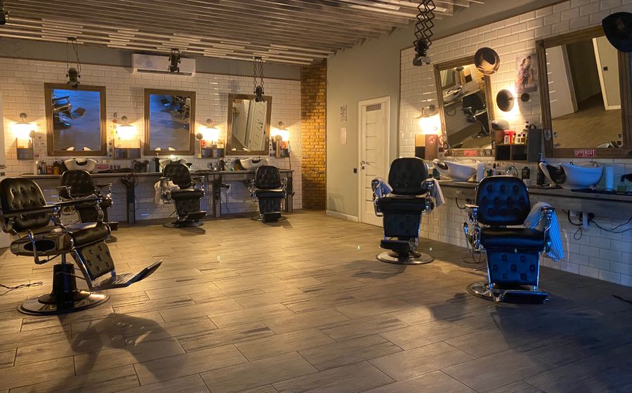 Peluquería vacía con los sillones de barbero frente a los espejos y los tocadores recogidos.